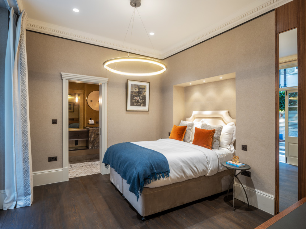 Mid-sized traditional guest bedroom in London with beige walls, dark hardwood floors, no fireplace, brown floor and wallpaper.