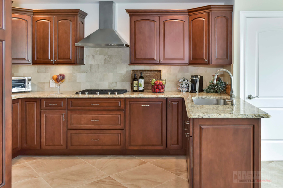 Inspiration for a mid-sized u-shaped eat-in kitchen in New York with an undermount sink, raised-panel cabinets, brown cabinets, granite benchtops, beige splashback, stainless steel appliances, a peninsula and beige benchtop.