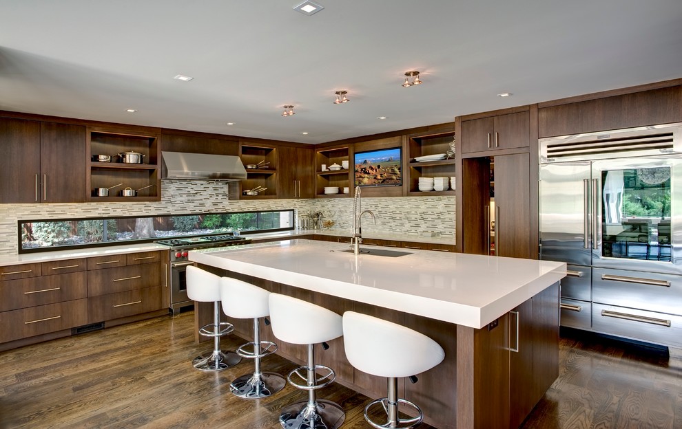 Photo of a contemporary l-shaped kitchen in Kansas City with stainless steel appliances, flat-panel cabinets, dark wood cabinets and matchstick tile splashback.