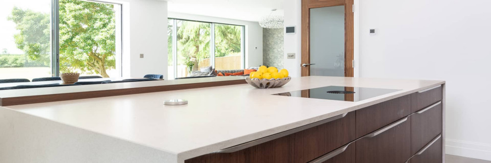 Immagine di una grande cucina chic con lavello da incasso, ante lisce, ante in legno bruno, top in quarzite, elettrodomestici neri e top bianco