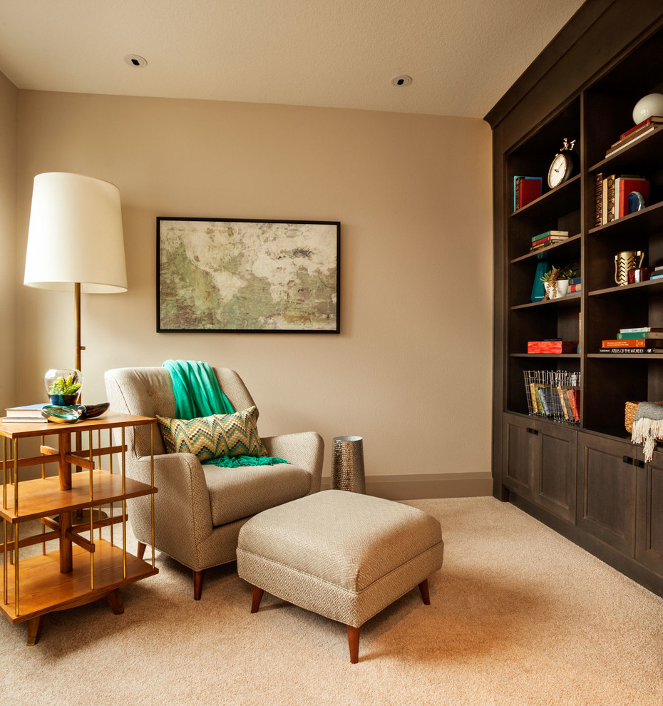 This is an example of a transitional family room in Portland with a library, beige walls and carpet.