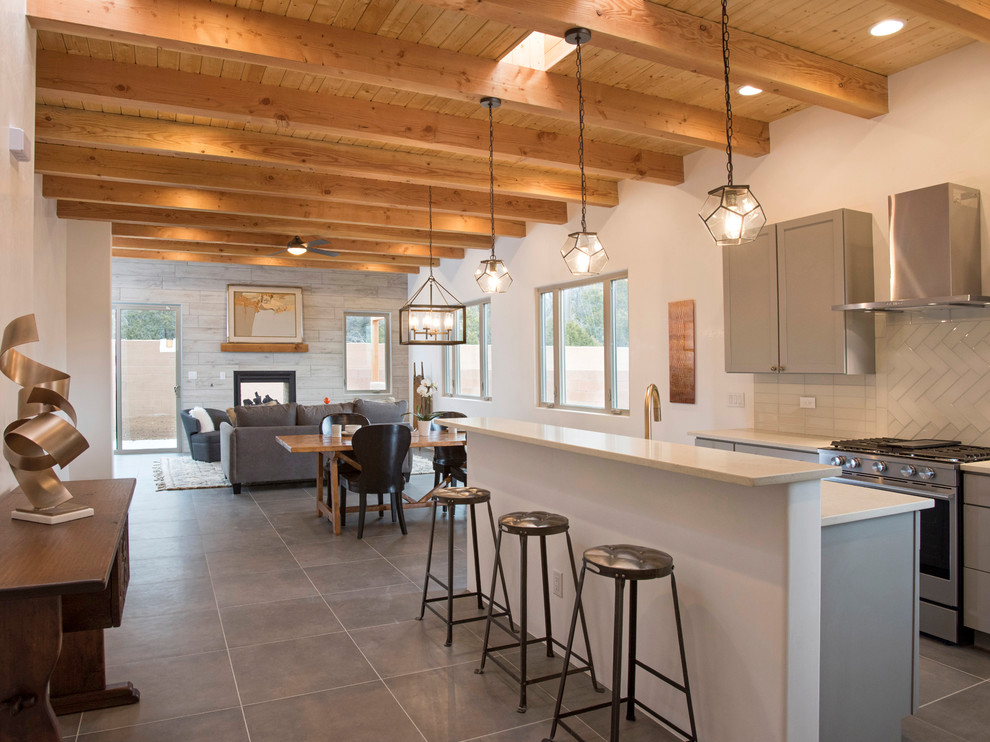Inspiration for a southwestern gray floor open concept kitchen remodel in Albuquerque with shaker cabinets, gray cabinets, white backsplash, glass tile backsplash, stainless steel appliances, an island and white countertops