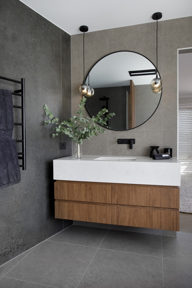 Design ideas for a mid-sized contemporary master wet room bathroom in Brisbane with flat-panel cabinets, medium wood cabinets, a freestanding tub, a one-piece toilet, gray tile, porcelain tile, grey walls, ceramic floors, engineered quartz benchtops, grey floor, an open shower, white benchtops, a niche, a single vanity and a floating vanity.