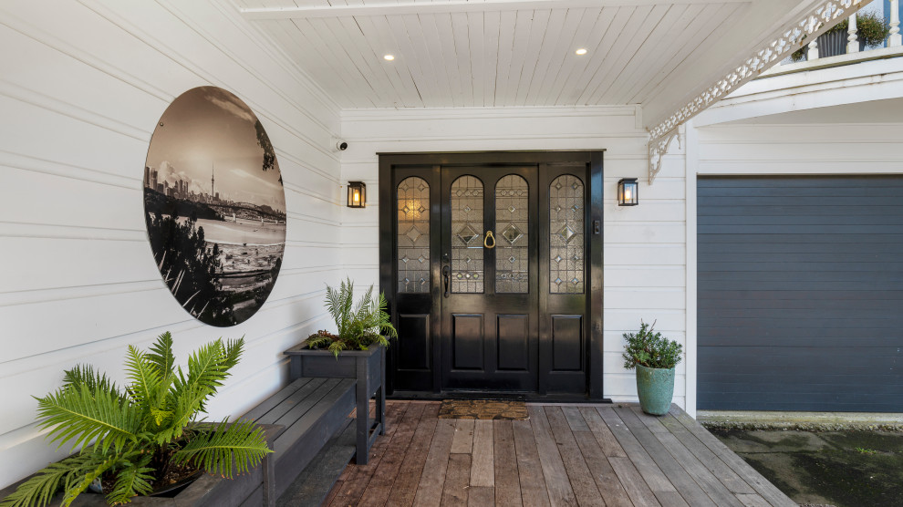 Große Mid-Century Haustür mit weißer Wandfarbe, Drehtür, dunkler Holzhaustür, Holzdielendecke und Wandpaneelen in Auckland