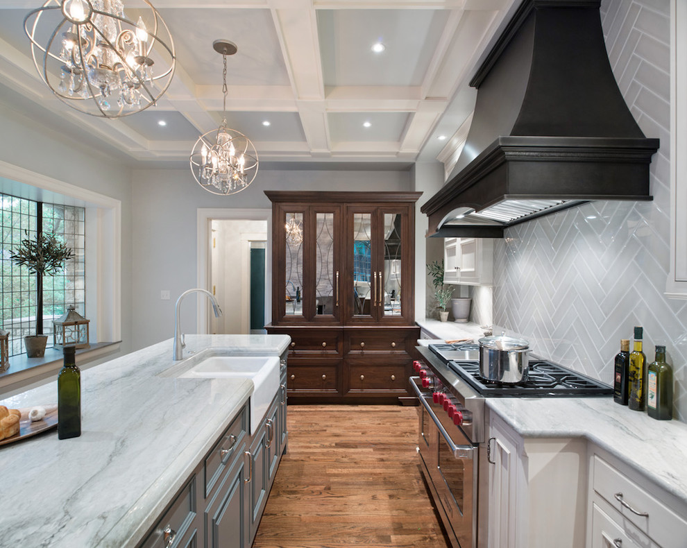 Traditional galley kitchen in Kansas City with a farmhouse sink, raised-panel cabinets, grey splashback, stainless steel appliances, light hardwood floors and with island.