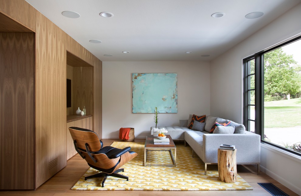 Midcentury family room in Austin with medium hardwood floors and a wall-mounted tv.