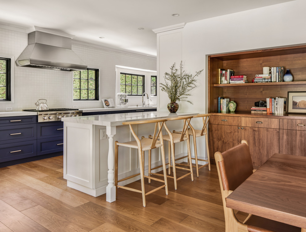 Design ideas for a mid-sized scandinavian eat-in kitchen in Los Angeles with shaker cabinets, blue cabinets, solid surface benchtops, white splashback, mosaic tile splashback, stainless steel appliances, medium hardwood floors, a peninsula, beige floor, white benchtop and a single-bowl sink.
