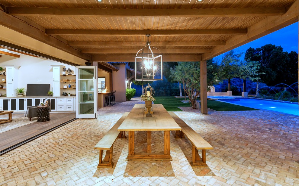 Design ideas for a mediterranean backyard patio in Phoenix with an outdoor kitchen, brick pavers and an awning.