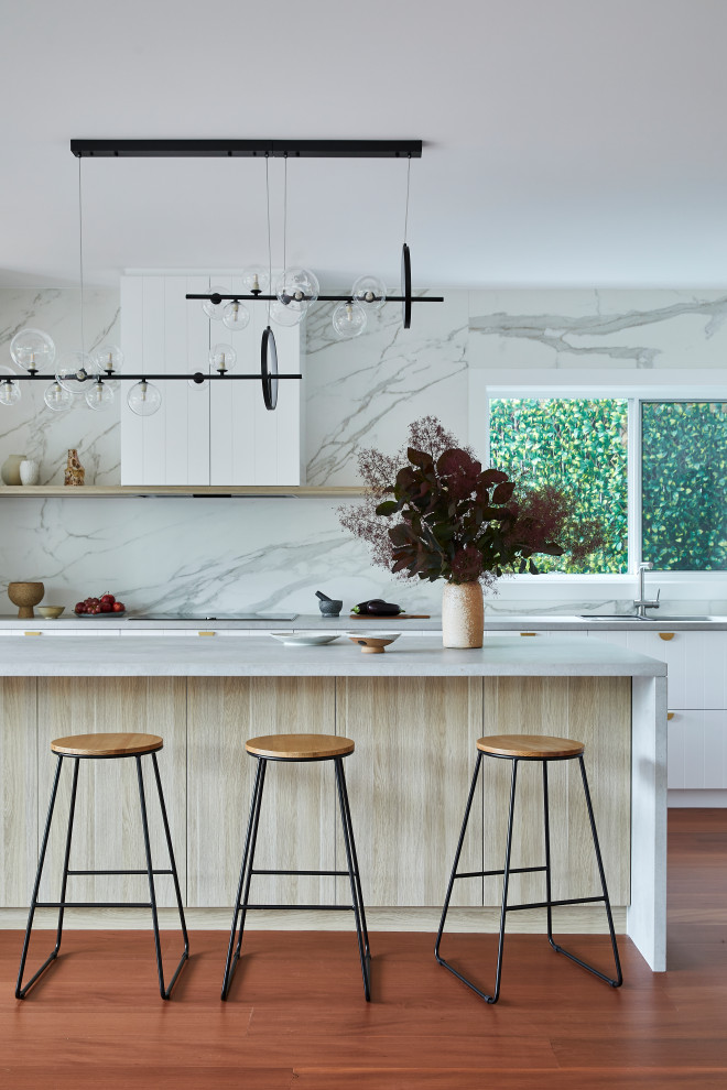 Photo of a large contemporary l-shaped eat-in kitchen in Sydney with a drop-in sink, shaker cabinets, white cabinets, quartz benchtops, white splashback, porcelain splashback, black appliances, dark hardwood floors, with island, brown floor and grey benchtop.