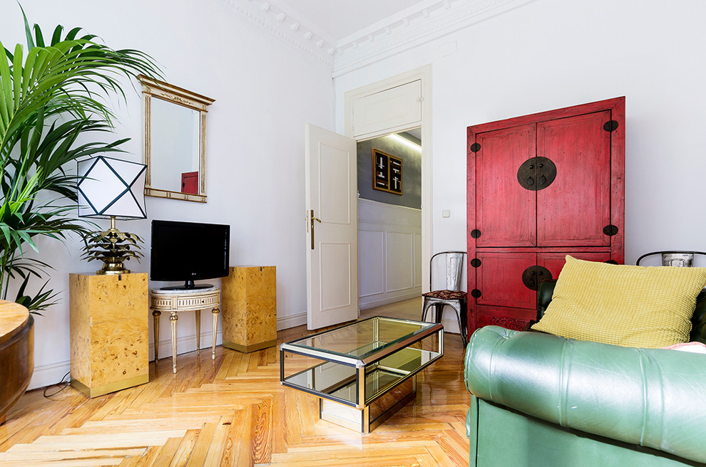 Inspiration for a mid-sized eclectic formal enclosed living room in Madrid with white walls, medium hardwood floors, no fireplace and a freestanding tv.