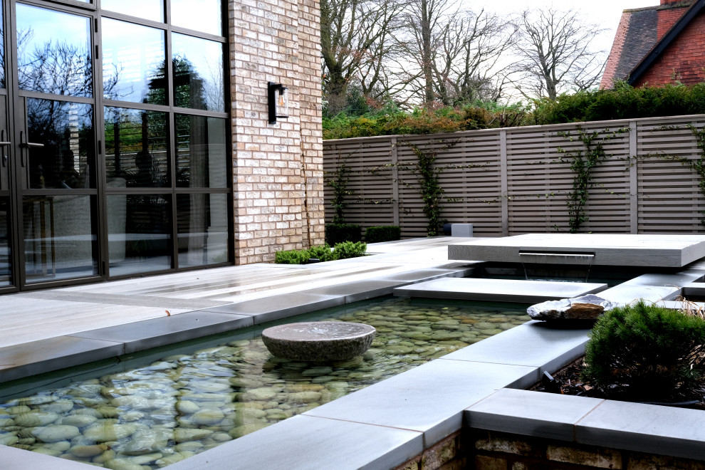 Geometrischer, Mittelgroßer Moderner Garten hinter dem Haus mit direkter Sonneneinstrahlung und Natursteinplatten in Cheshire