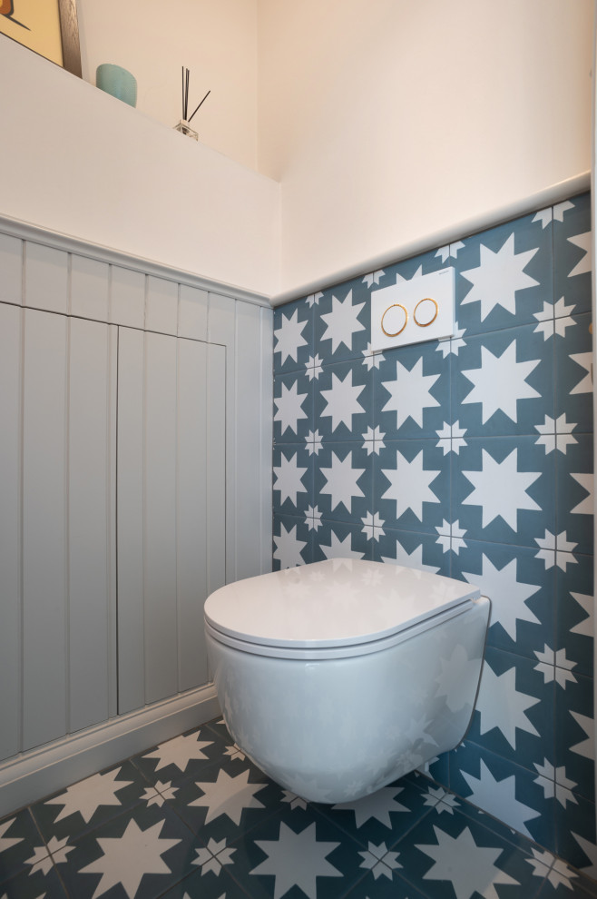 Photo of a medium sized classic cloakroom in London with a wall mounted toilet, blue tiles, porcelain tiles, pink walls, porcelain flooring, a wall-mounted sink, blue floors, a dado rail and panelled walls.
