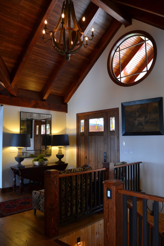 Example of a large mountain style medium tone wood floor foyer design with white walls and a medium wood front door