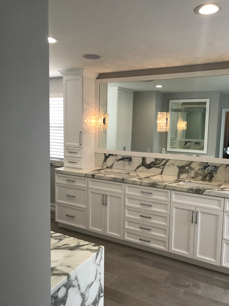Photo of a large transitional master bathroom in Miami with shaker cabinets, white cabinets, an undermount tub, a corner shower, black and white tile, gray tile, stone slab, grey walls, medium hardwood floors, an undermount sink, marble benchtops, brown floor and a hinged shower door.