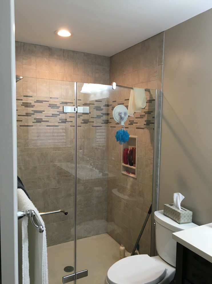 Small transitional 3/4 alcove shower photo in Baltimore with black cabinets, a one-piece toilet, brown walls, an undermount sink, solid surface countertops, a hinged shower door and white countertops