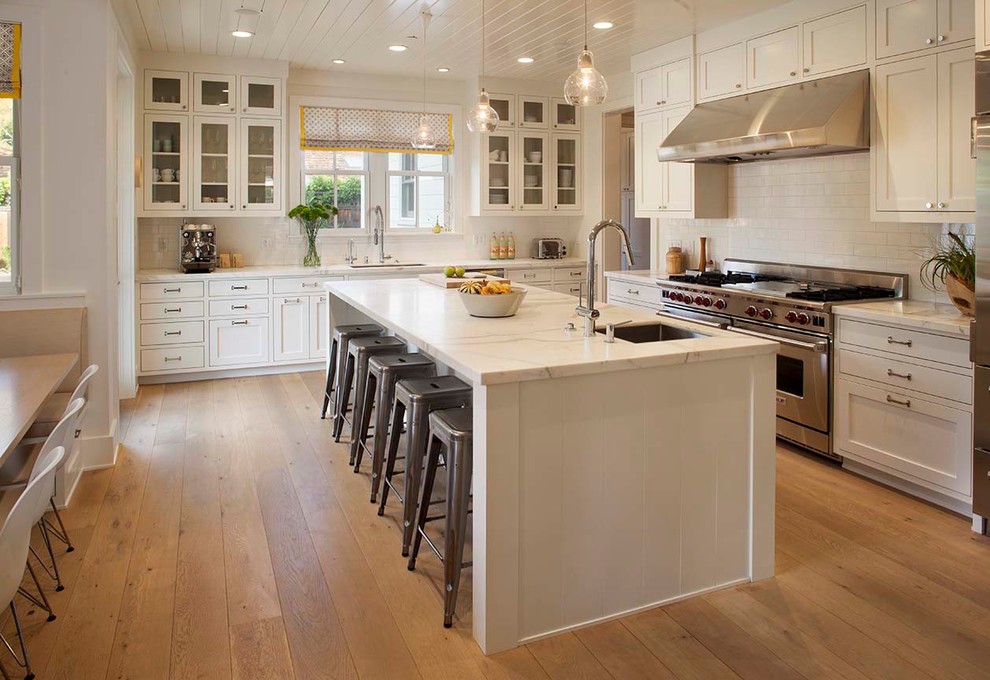 Design ideas for a country galley eat-in kitchen in San Francisco with an undermount sink, shaker cabinets, white cabinets, white splashback, subway tile splashback, stainless steel appliances, medium hardwood floors and with island.