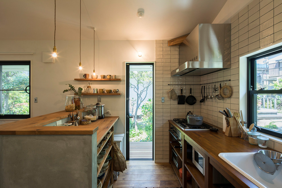 This is an example of a small industrial galley open plan kitchen in Other with a drop-in sink, open cabinets, medium wood cabinets, wood benchtops, medium hardwood floors, with island and brown floor.