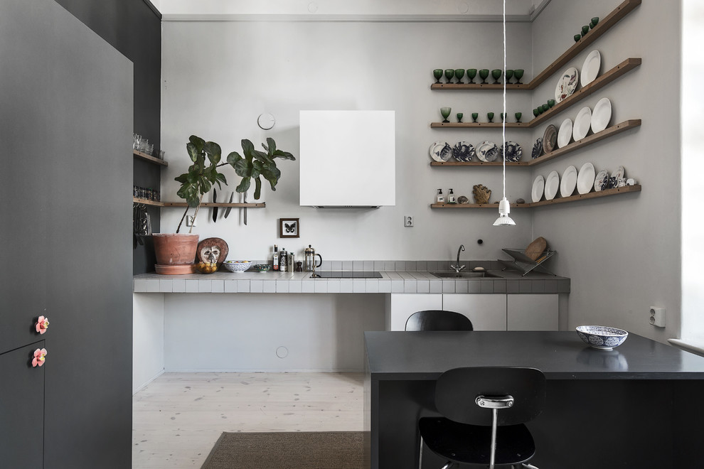 Mid-sized scandinavian single-wall eat-in kitchen in Stockholm with open cabinets, tile benchtops, white splashback, light hardwood floors and no island.