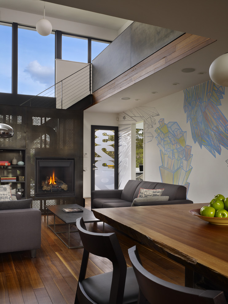 This is an example of a small modern open concept living room in Seattle with a standard fireplace, white walls, medium hardwood floors and a metal fireplace surround.