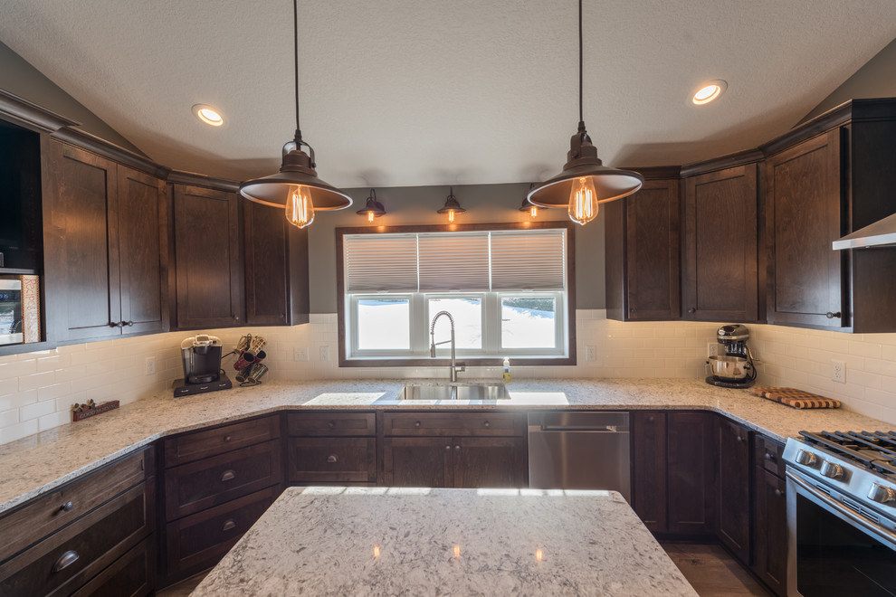 Inspiration for a large rustic u-shaped dark wood floor and brown floor enclosed kitchen remodel in Minneapolis with a double-bowl sink, shaker cabinets, dark wood cabinets, granite countertops, white backsplash, subway tile backsplash, stainless steel appliances and an island