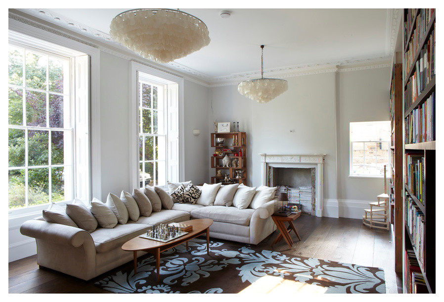 This is an example of a country living room in London with white walls, light hardwood floors and a standard fireplace.
