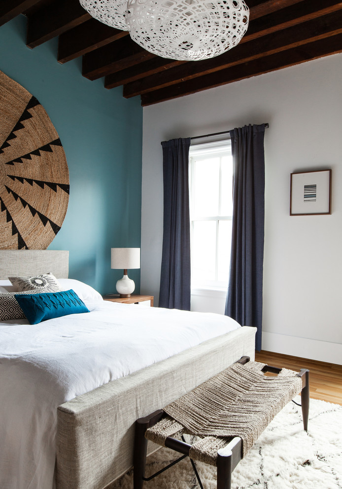 This is an example of a mid-sized eclectic master bedroom in New York with blue walls, light hardwood floors and no fireplace.