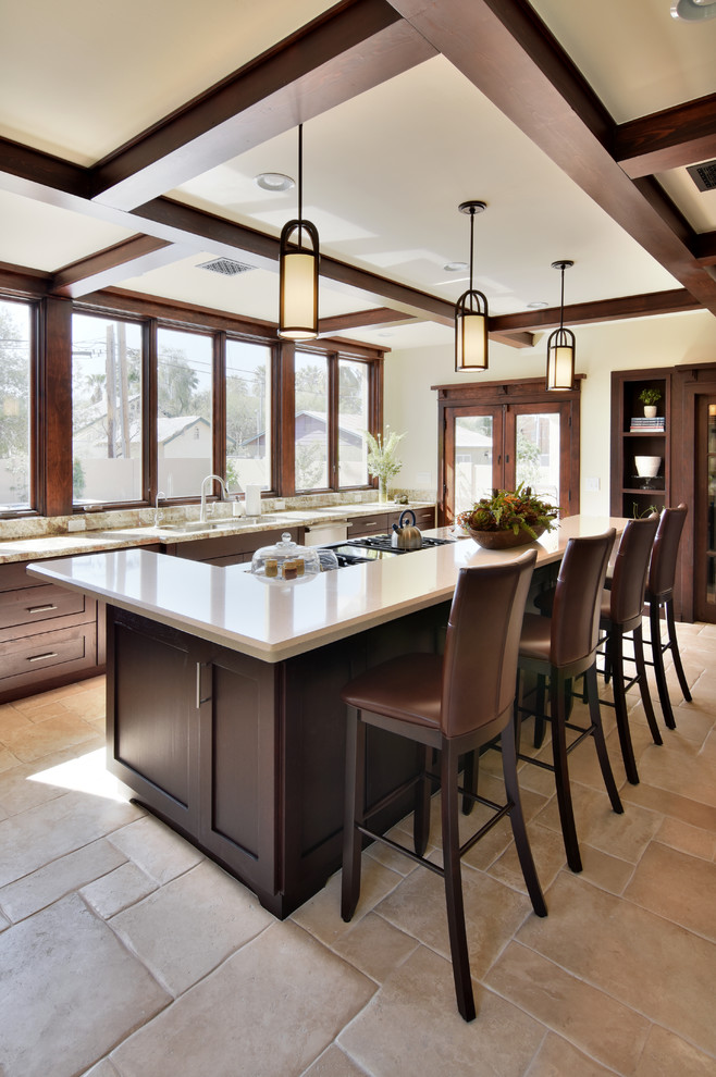 Large arts and crafts kitchen pantry in Phoenix with a double-bowl sink, shaker cabinets, dark wood cabinets, solid surface benchtops, stainless steel appliances, travertine floors and with island.