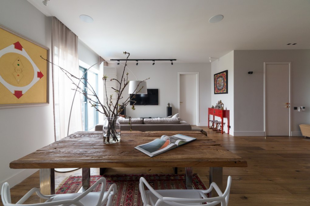 Immagine di un soggiorno moderno di medie dimensioni e aperto con pareti bianche, pavimento in legno massello medio, pavimento marrone e TV a parete