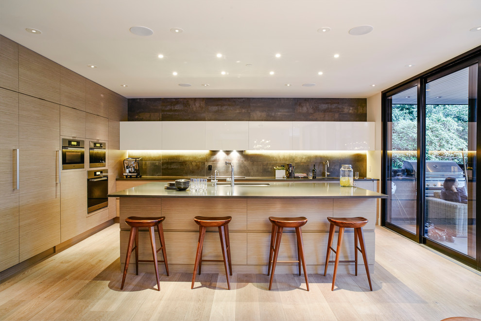 Contemporary l-shaped kitchen in Vancouver with an undermount sink, flat-panel cabinets, light wood cabinets, quartz benchtops, porcelain splashback, stainless steel appliances, light hardwood floors and with island.