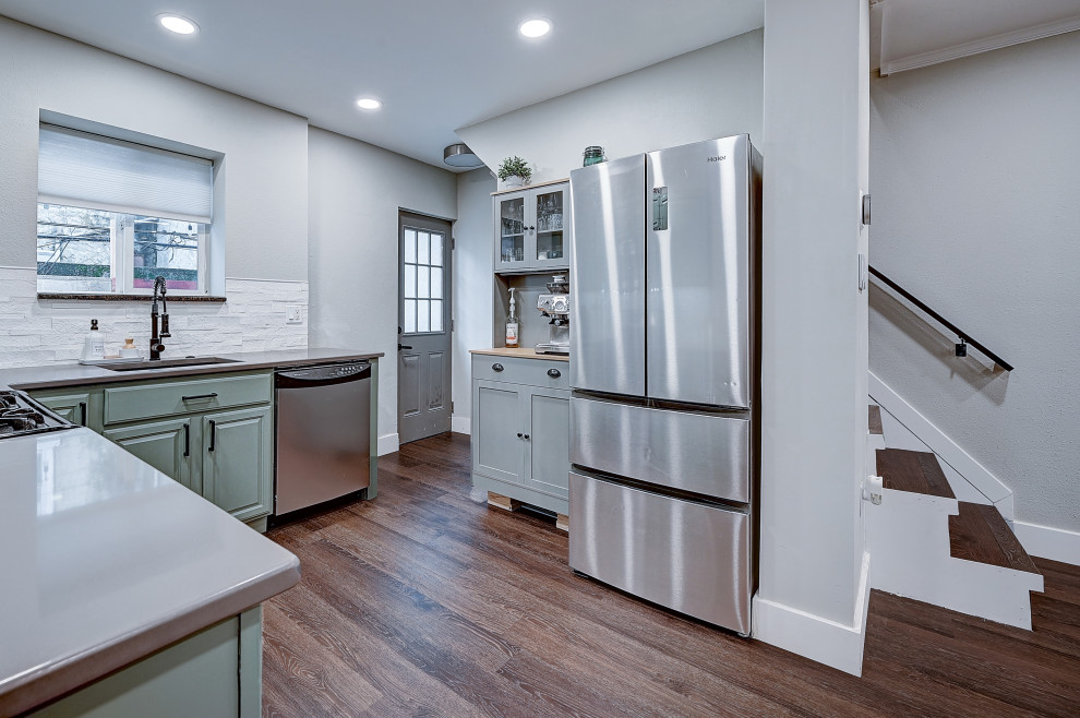 Bild på ett litet skandinaviskt grå grått kök, med en nedsänkt diskho, luckor med profilerade fronter, gröna skåp, bänkskiva i rostfritt stål, vitt stänkskydd, stänkskydd i kalk, rostfria vitvaror, vinylgolv, flera köksöar och brunt golv