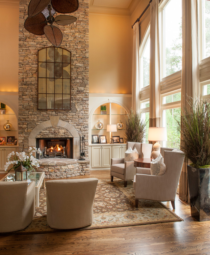Photo of a mid-sized traditional formal open concept living room in Atlanta with beige walls, medium hardwood floors, a standard fireplace, a stone fireplace surround, no tv and brown floor.