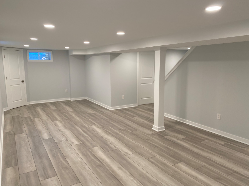 Photo of a large contemporary walk-out basement in Philadelphia with grey walls, laminate floors and brown floors.