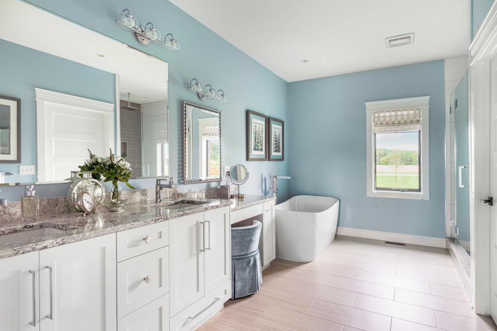 Cette image montre une grande salle de bain principale rustique avec un placard à porte shaker, des portes de placard blanches, une baignoire indépendante, une douche double, WC à poser, un carrelage bleu, un mur bleu, un lavabo encastré, un plan de toilette en marbre, un sol beige, une cabine de douche à porte battante, un plan de toilette beige, meuble double vasque et meuble-lavabo encastré.