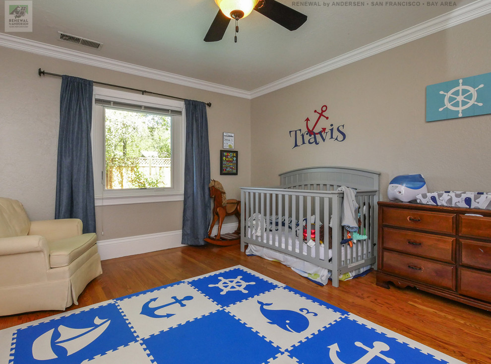 Nursery - mid-sized boy medium tone wood floor and multicolored floor nursery idea in San Francisco with beige walls