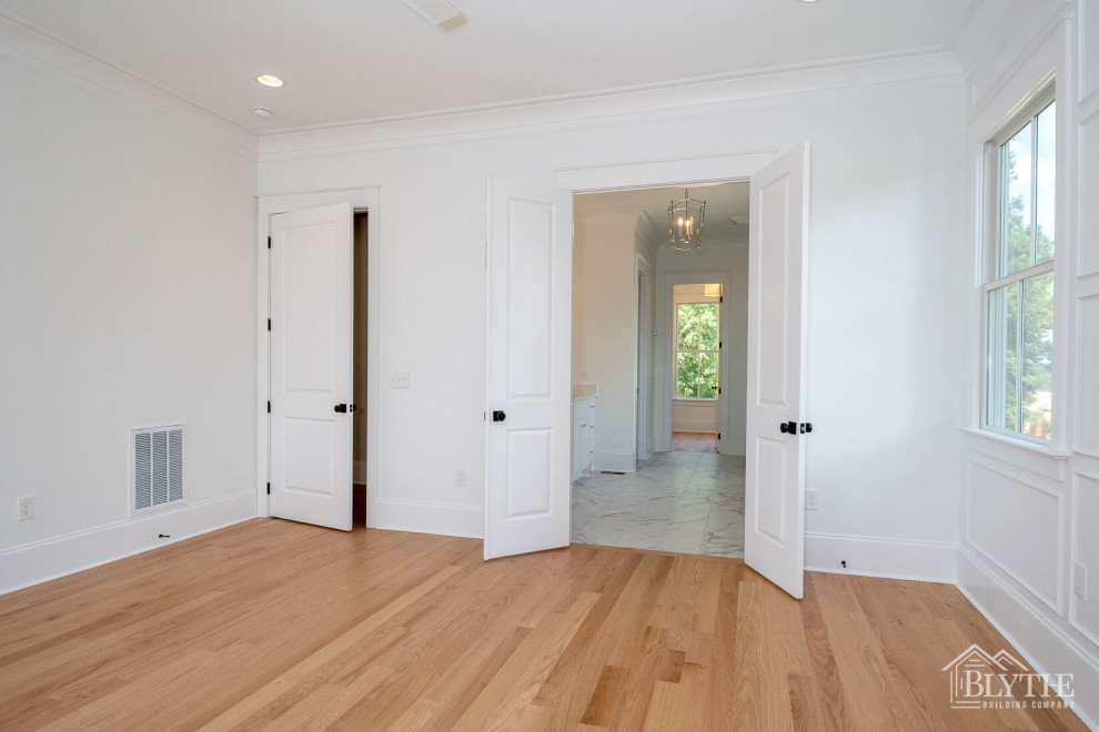 Photo of a mid-sized arts and crafts master bedroom in Other with white walls, light hardwood floors and brown floor.
