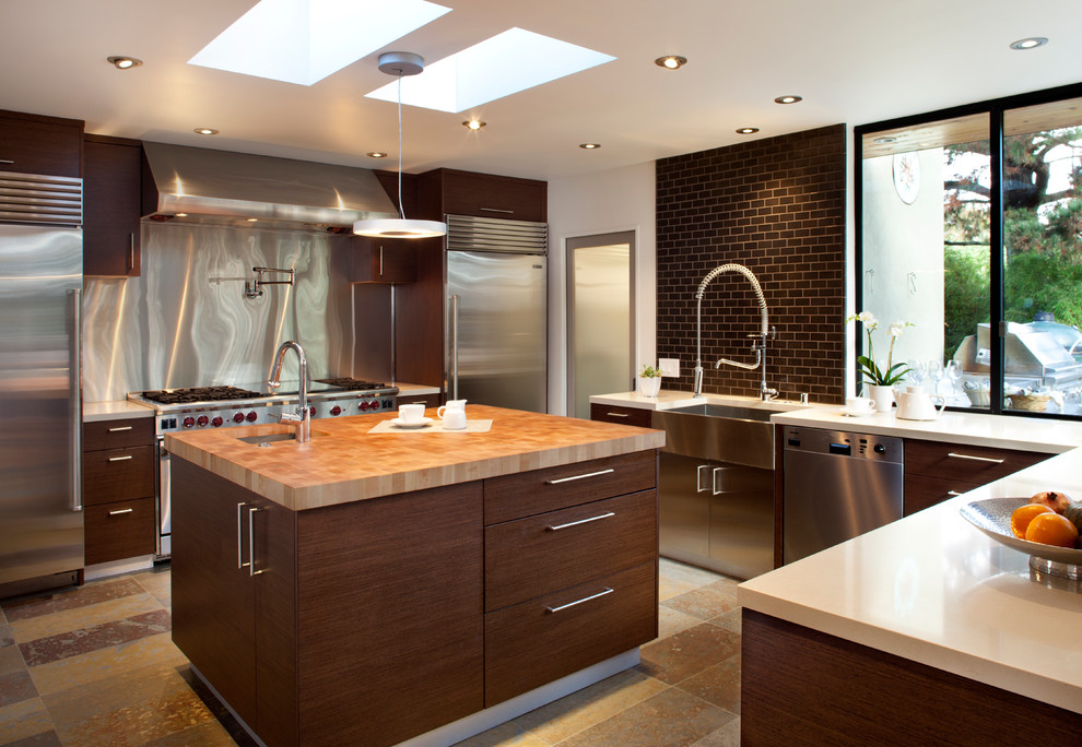 Design ideas for a mid-sized contemporary eat-in kitchen in San Francisco with stainless steel appliances, a farmhouse sink, quartz benchtops, flat-panel cabinets, dark wood cabinets, brown splashback, subway tile splashback, slate floors, brown floor and beige benchtop.