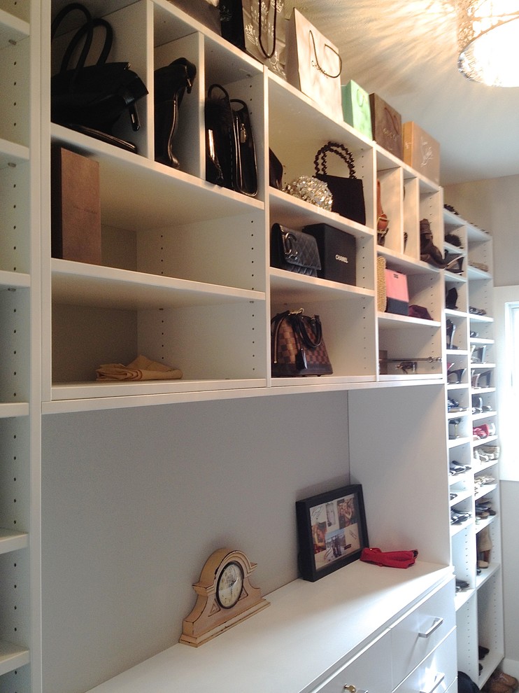 This is an example of a mid-sized gender-neutral walk-in wardrobe in Other with white cabinets and carpet.