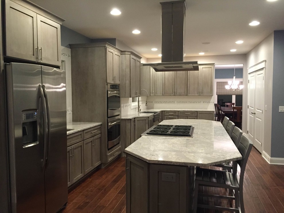 Large transitional l-shaped medium tone wood floor eat-in kitchen photo in Grand Rapids with a farmhouse sink, shaker cabinets, gray cabinets, quartz countertops, white backsplash, porcelain backsplash, stainless steel appliances and an island