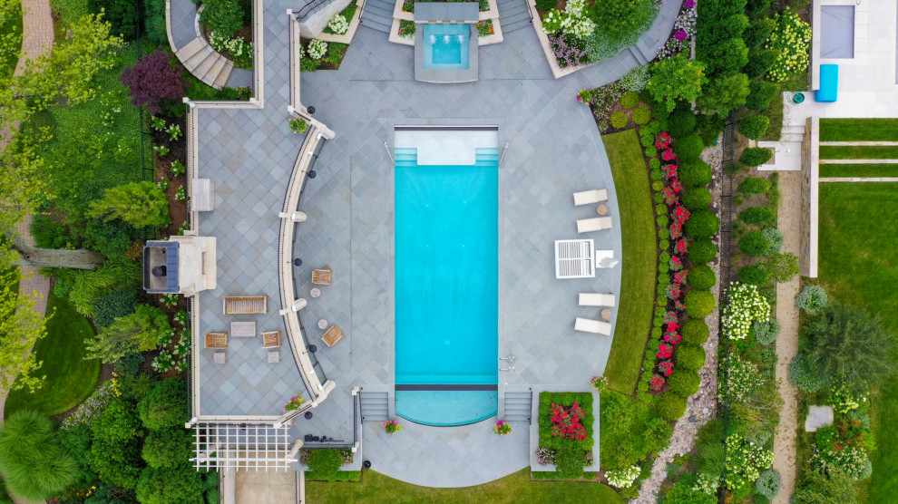 This is an example of a medium sized traditional courtyard rectangular lengths swimming pool in Chicago with with pool landscaping and natural stone paving.