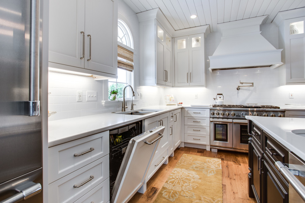Large transitional kitchen in DC Metro with an undermount sink, recessed-panel cabinets, quartz benchtops, white splashback, subway tile splashback, stainless steel appliances and with island.