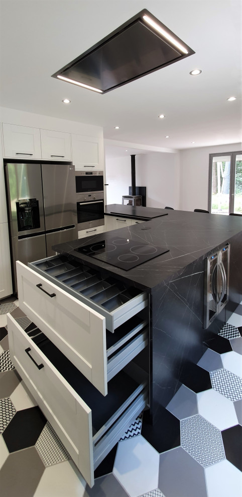 Photo of a large contemporary u-shaped open plan kitchen in Other with an undermount sink, flat-panel cabinets, stainless steel cabinets, granite benchtops, black splashback, granite splashback, panelled appliances, ceramic floors, with island, white floor and black benchtop.