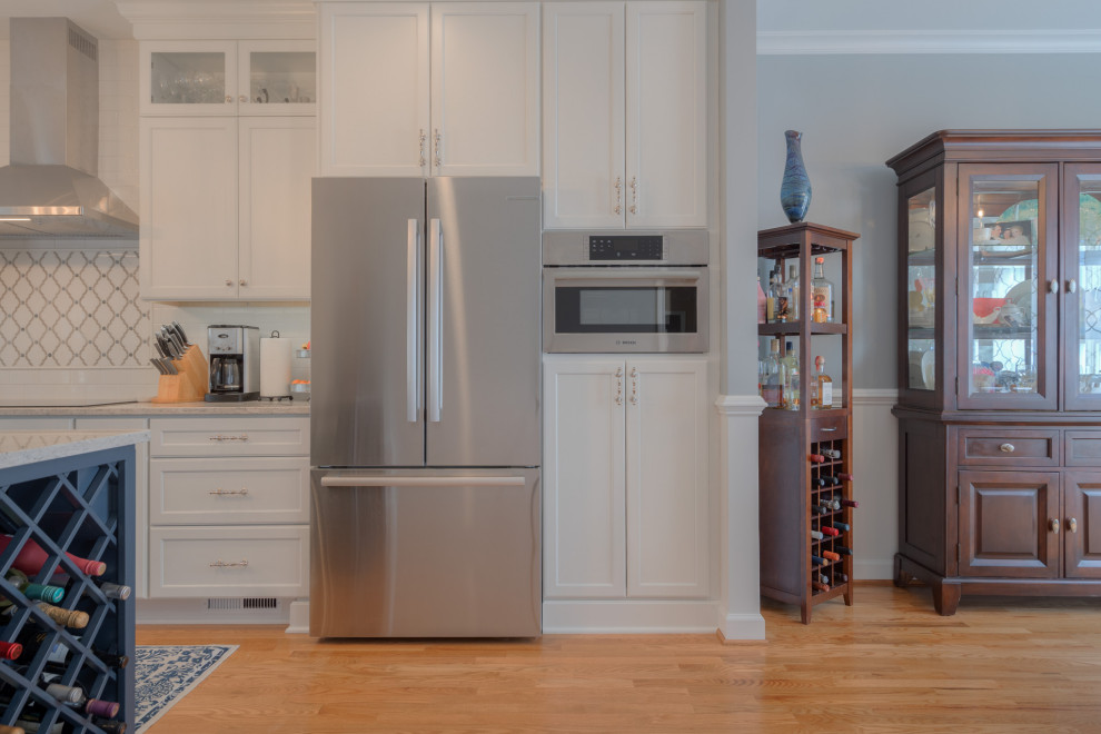 Eat-in kitchen - mid-sized transitional galley medium tone wood floor eat-in kitchen idea with an undermount sink, flat-panel cabinets, white cabinets, quartz countertops, white backsplash, subway tile backsplash, stainless steel appliances, an island and white countertops