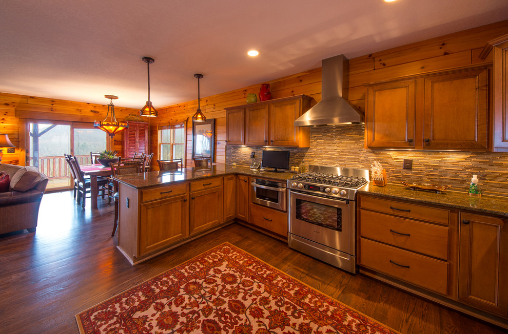 Example of a mid-sized mountain style u-shaped kitchen pantry design with an undermount sink, shaker cabinets, medium tone wood cabinets, laminate countertops, gray backsplash, glass tile backsplash, stainless steel appliances, gray walls, engineered wood floors and a peninsula