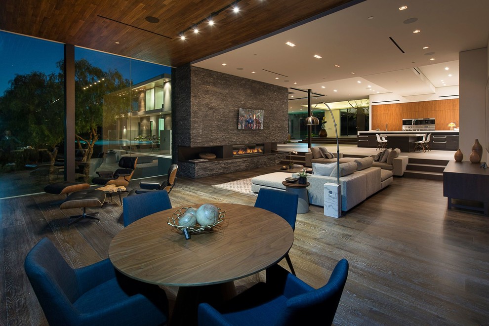 Inspiration for an expansive modern formal mezzanine living room in Los Angeles with multi-coloured walls, medium hardwood flooring, a standard fireplace, a stacked stone fireplace surround, a wall mounted tv, beige floors and a drop ceiling.