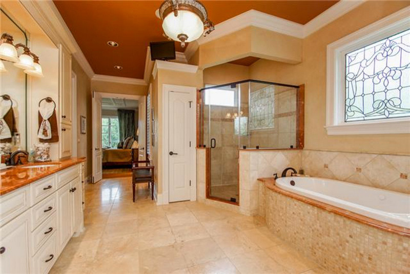This is an example of a large traditional master bathroom in Nashville with white cabinets, marble benchtops, a corner shower and beige tile.