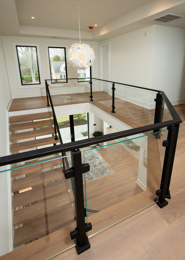 Design ideas for an expansive transitional wood floating staircase in DC Metro with open risers and metal railing.