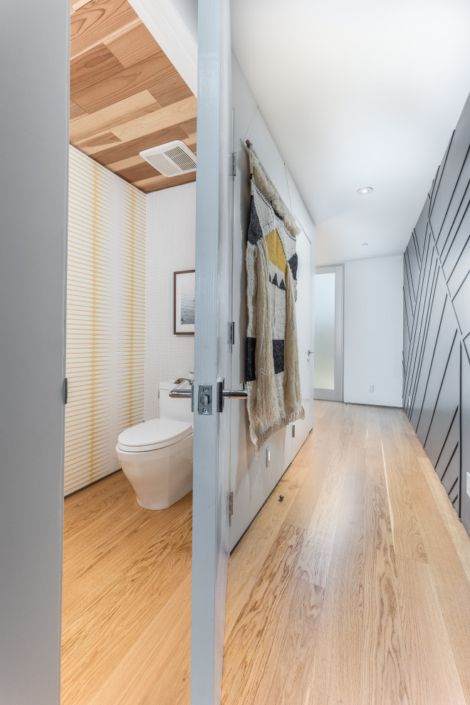 Cette image montre un petit WC et toilettes design en bois brun avec WC à poser, un carrelage blanc, une plaque de galets, un lavabo intégré, un plan de toilette blanc, meuble-lavabo encastré, un plafond en bois et du papier peint.