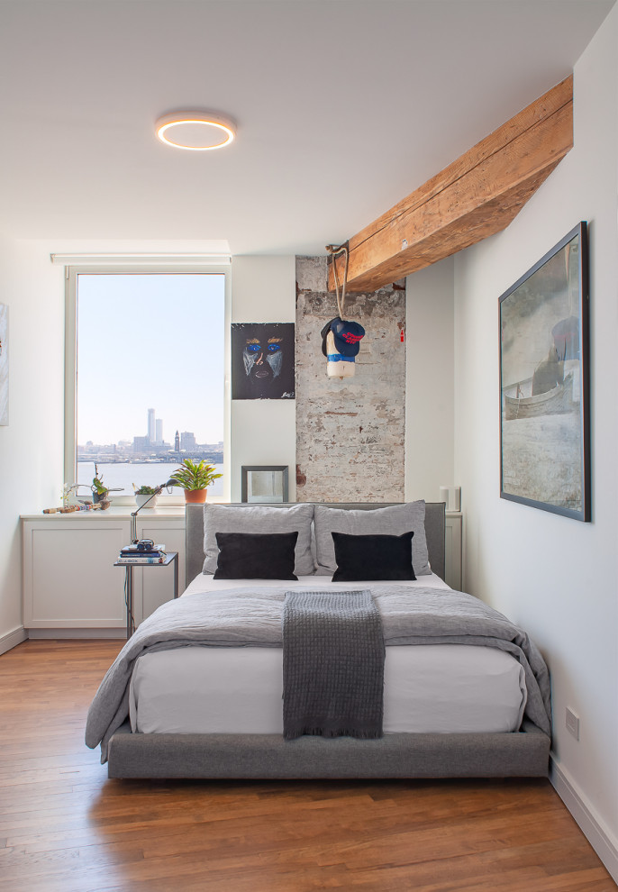Example of a trendy guest medium tone wood floor and exposed beam bedroom design in New York with white walls
