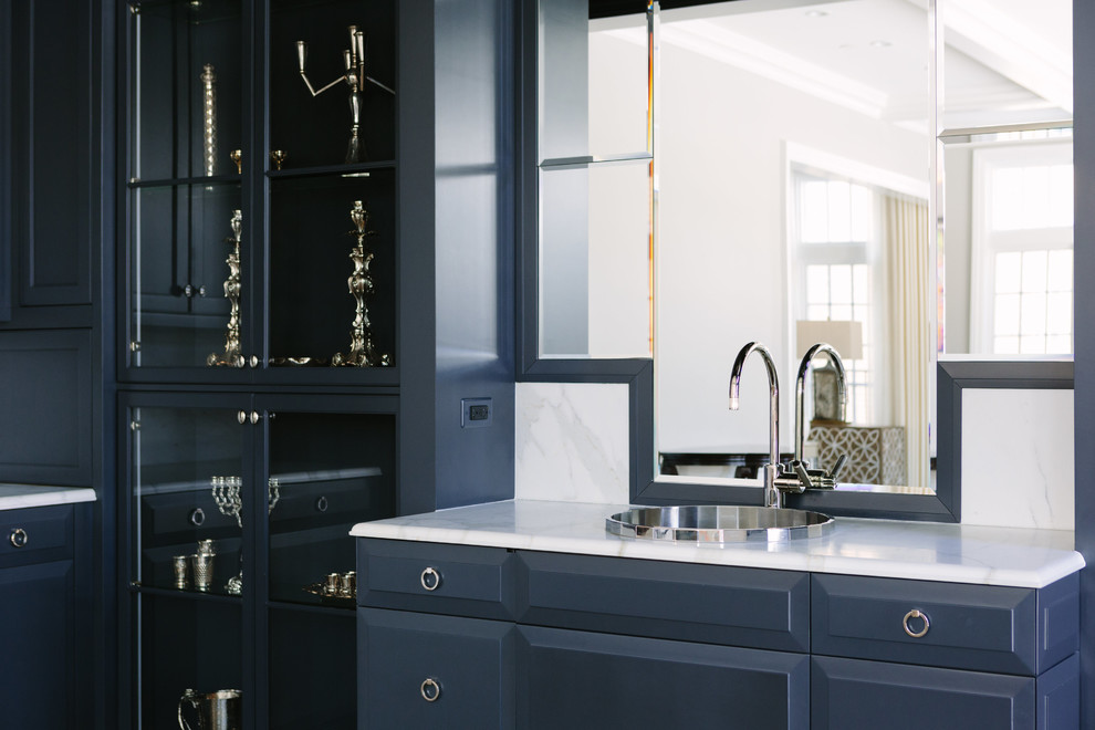 Large transitional l-shaped wet bar photo in Chicago with a drop-in sink, beaded inset cabinets, blue cabinets, marble countertops, white backsplash, mirror backsplash and white countertops