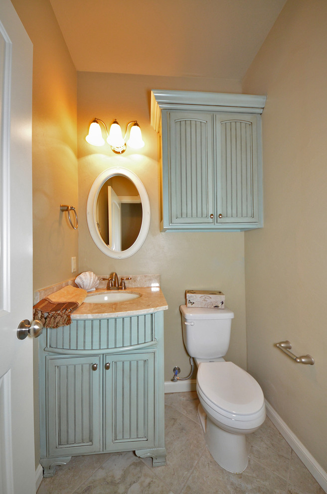 This is an example of a small transitional powder room in Oklahoma City with an undermount sink, beaded inset cabinets, engineered quartz benchtops, a two-piece toilet, beige walls and ceramic floors.